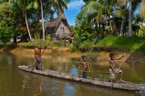 Rencontre d'une pirogue sur le fleuve Sepik devant la maison des esprits du village de Kabriman