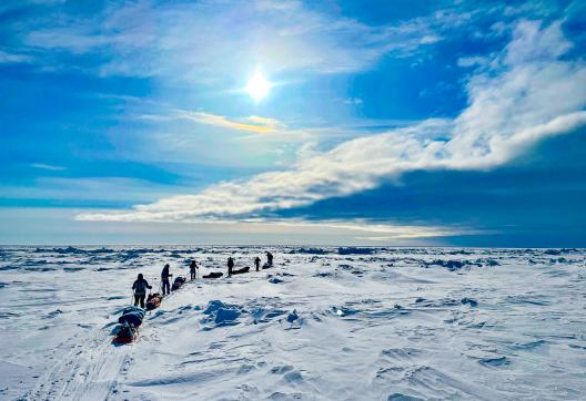 Expédition avec skieurs qui se suivent sous un nuage menaçant