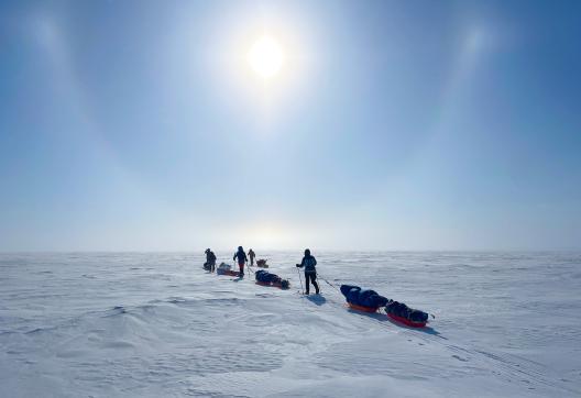 Expedition avec des skieurs qui avancent face au soleil lenticulaire au canada