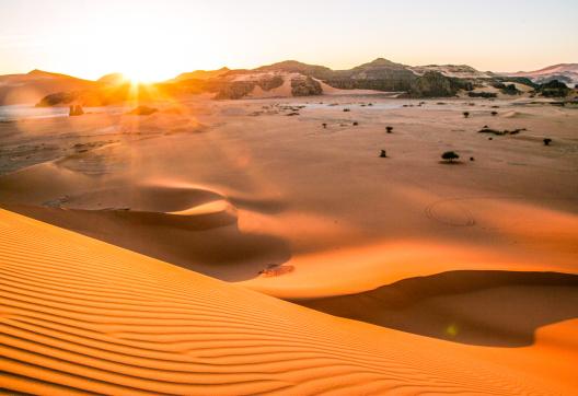 Trek dans les dunes de la Tadrart au soleil couchant en Algérie