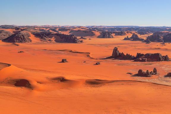 Trek sur un plateau de dunes ocres et hautes falaises dans la Tadrart